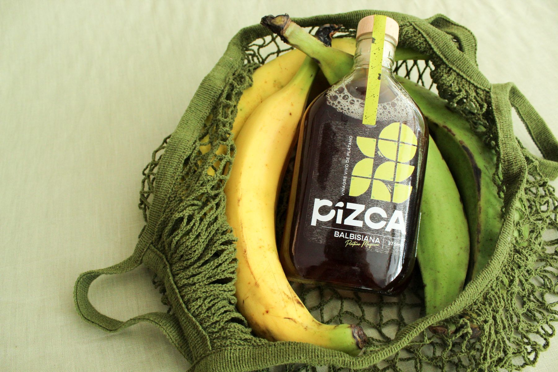 Botella Pizca Balbisiana con plátanos maduros y verdes en una malla