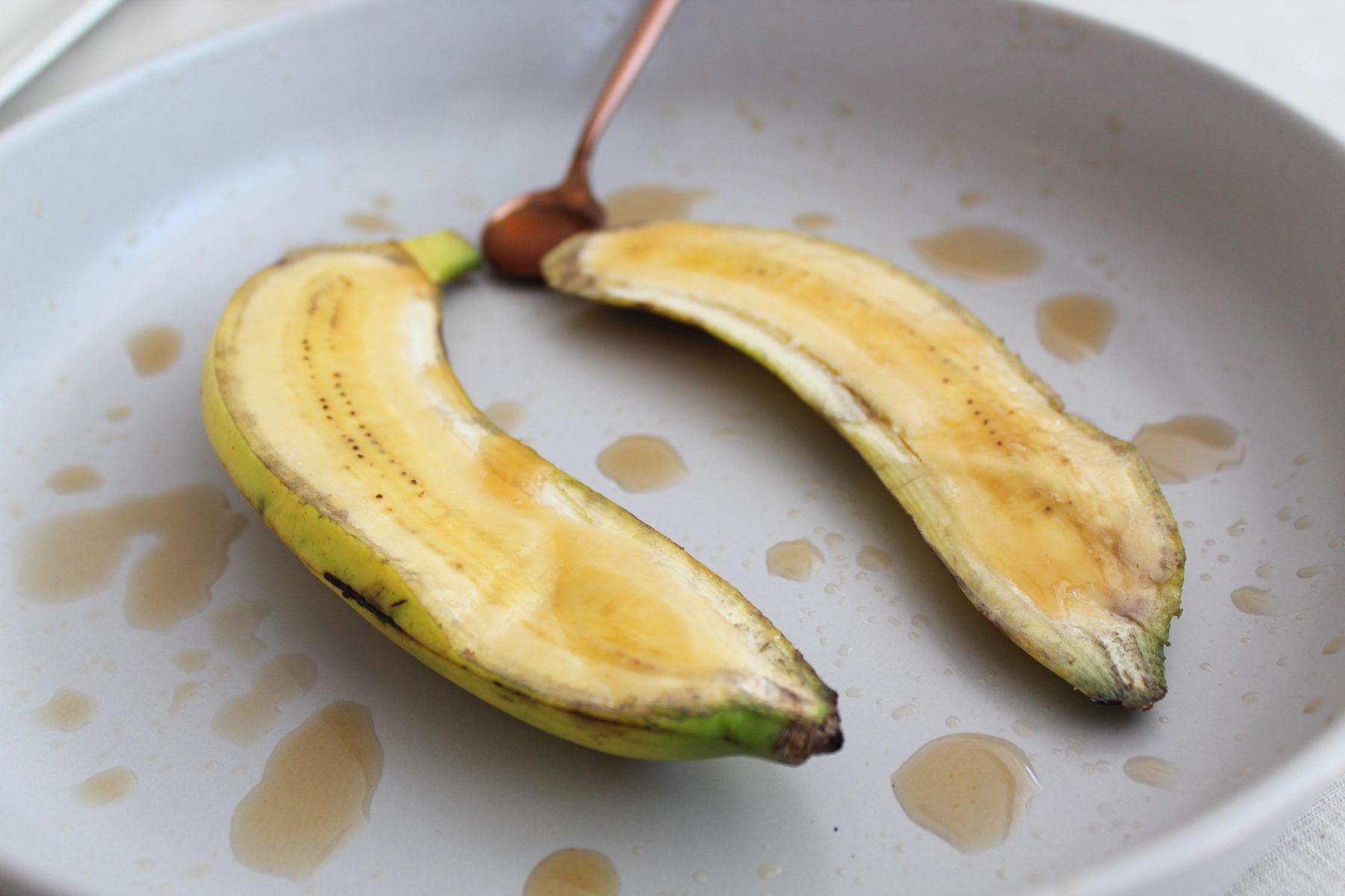 Roasted plantain split open with drops of vinegar on a plate